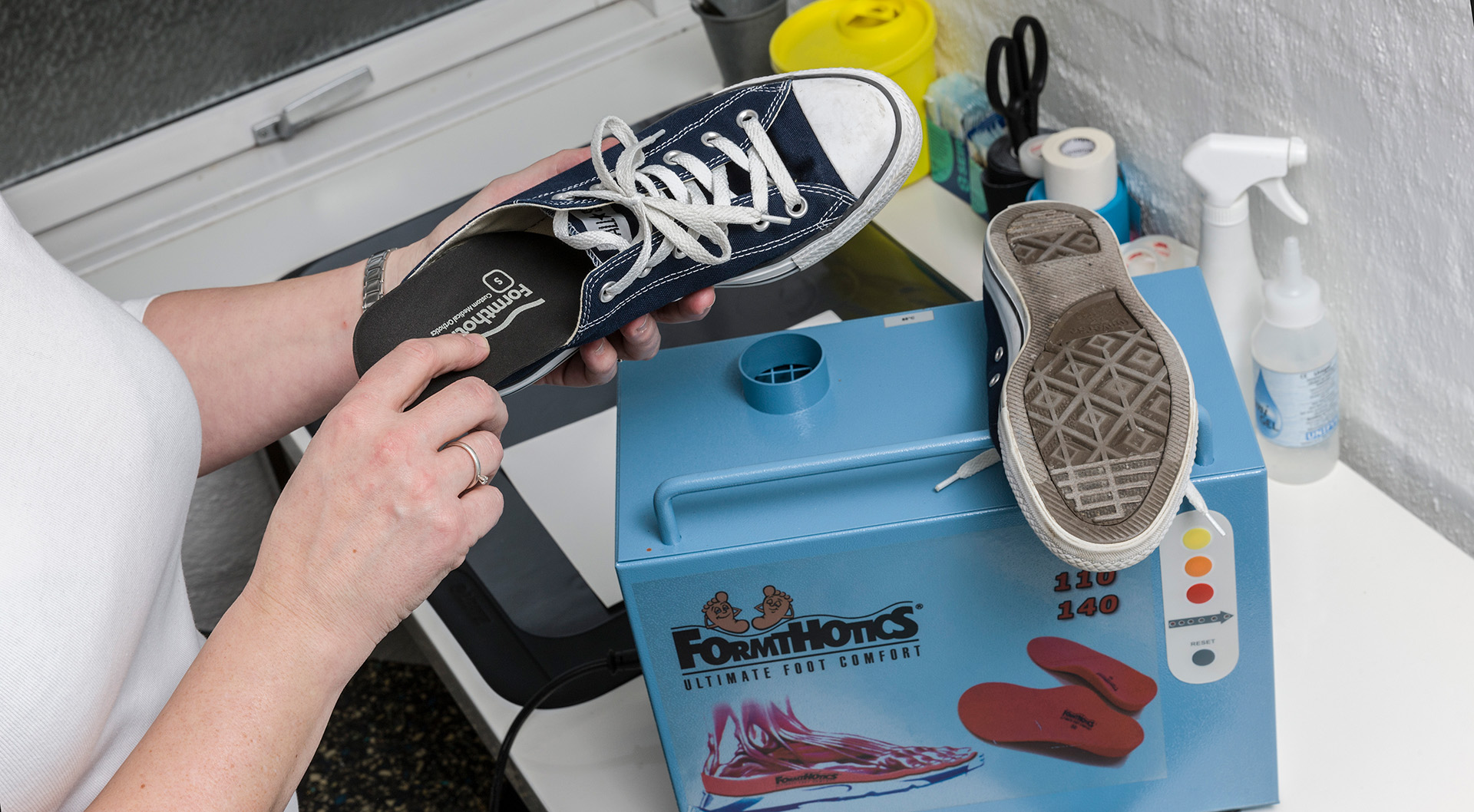 Fysioterapeut isætter nyformede indlægssåler fra FormHotics i klients sko