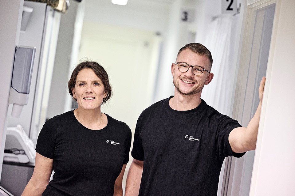 Fysioterapeuterne Maiken Hansen og Herman Strand står parat i døråbningen til smilende at modtage dagens klienter